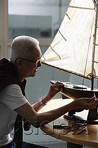 AsiaPix - profile of older man working on model sail boat