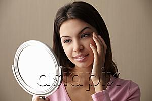 AsiaPix - young woman looking at mirror touching her face