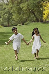 Asia Images Group - two little children running through a park holding hands