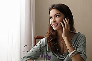 AsiaPix - young woman talking on phone looking out window