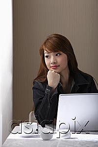 AsiaPix - Young woman sitting at table with laptop