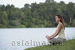 Asia Images Group - Woman meditating by lake