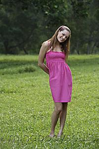 Mind Body Soul - Woman in pink dress standing on grass and smiling out side.
