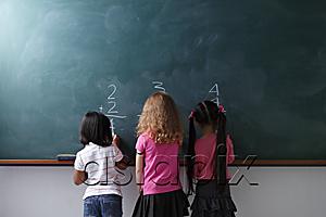 AsiaPix - rear view of 3 young girls writing on chalk board