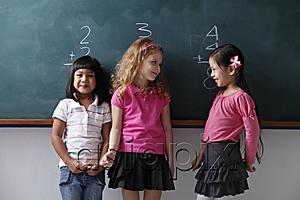 AsiaPix - three young girls standing in front of a chalk board, smiling at each other