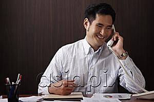 AsiaPix - man sitting at desk talking on phone