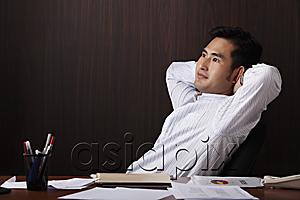 AsiaPix - man relaxing at work with hands behind his head