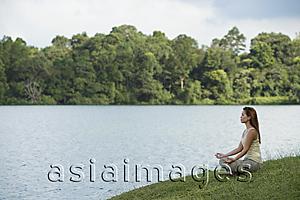 Asia Images Group - Young woman meditating beside a lake