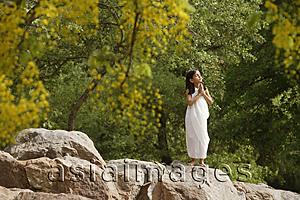 Asia Images Group - girl in white sari, standing in yoga pose on rock