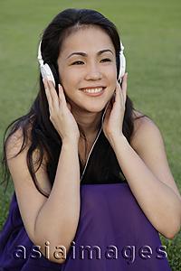 Asia Images Group - Portrait of young woman listening to music at park