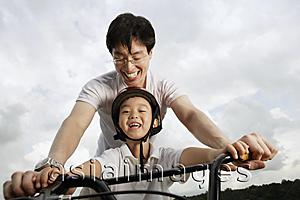 Asia Images Group - Father teaching son how to ride bike