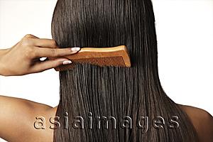 Asia Images Group - woman pulling comb through her hair