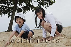 Asia Images Group - boy and girl playing in sand near ocean
