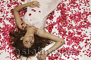 Asia Images Group - woman lying surrounded by rose petals