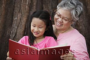 Asia Images Group - Older woman reading book to young girl.