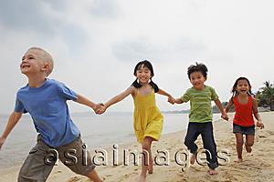 Asia Images Group - Four kids running down the beach holding hands.