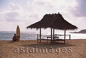 Asia Images Group - A surfer holding a surf board sitting on the beach, Catanduanes, Philippines