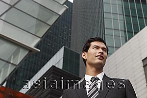 Asia Images Group - business man in suit standing among tall buildings