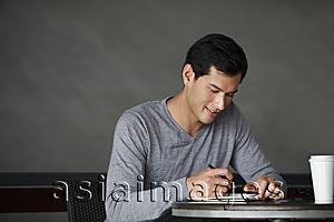 Asia Images Group - man writing in a book, smiling slightly