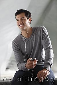 Asia Images Group - man listening to music with earphones, smiling