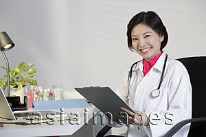 Asia Images Group - Woman Doctor working at desk and smiling