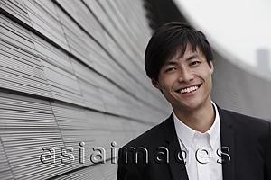 Asia Images Group - Chinese man smiling at camera in front of building