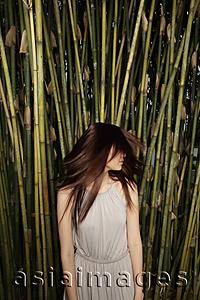 Asia Images Group - Young woman shaking her hair in front of bamboo