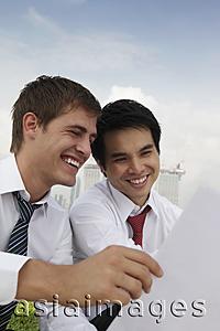 Asia Images Group - Two business men smiling and looking at paper