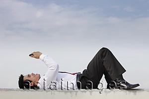 Asia Images Group - man in suit laying on ground looking at phone, smiling