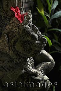 Asia Images Group - red hibiscus in stone Hindu statue