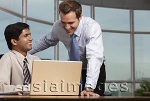 Asia Images Group - Caucasian man looking at laptop with Indian man and smiling
