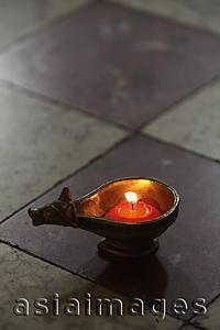 Asia Images Group - lit candle in bronze cow dish