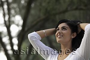Asia Images Group - Head shot of young woman looking up and smiling with hands in hair