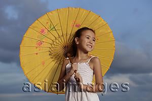 Asia Images Group - young girl smiling holding yellow Chinese umbrella, blue sky background