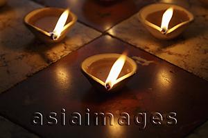 Asia Images Group - Lit clay oil lamps on floor