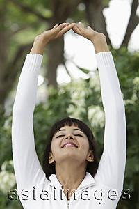 Asia Images Group - Head shot of woman stretching with arms over head