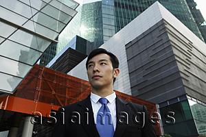 Asia Images Group - Young man wearing a suit standing in front of modern buildings