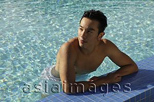 Asia Images Group - Young man resting on side of swimming pool