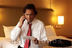 Asia Images Group - Man holding ticket and phone and frowning