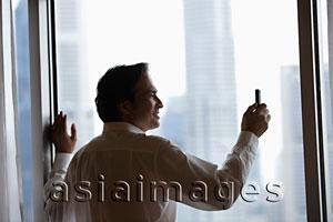 Asia Images Group - profile of businessman taking a photo with phone