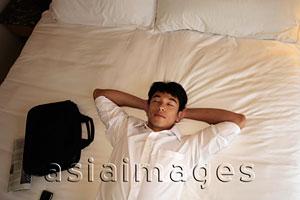 Asia Images Group - Man laying down on bed with eyes closed
