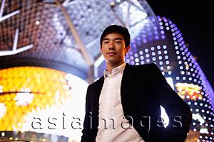 Asia Images Group - Young man in suit in front of lit building at night