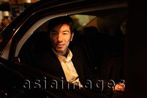 Asia Images Group - Young man sitting in car looking out of window at night