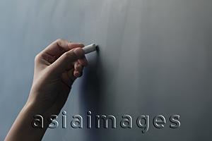Asia Images Group - Close up of hand holding piece of chalk on chalkboard