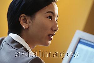 Asia Images Group - Female executive in front of computer monitor, profile, yellow background