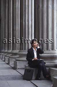 Asia Images Group - Female executive sitting, using cellular phone