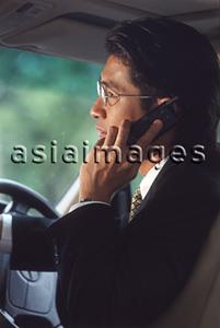 Asia Images Group - Male executive talking on cellular phone in car, profile