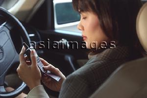 Asia Images Group - Female executive using cellular phone in car, profile