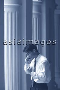 Asia Images Group - Male executive talking on cellular phone, pillars behind