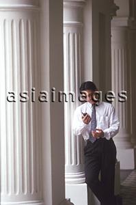 Asia Images Group - Male executive looking at cellular phone, pillars behind